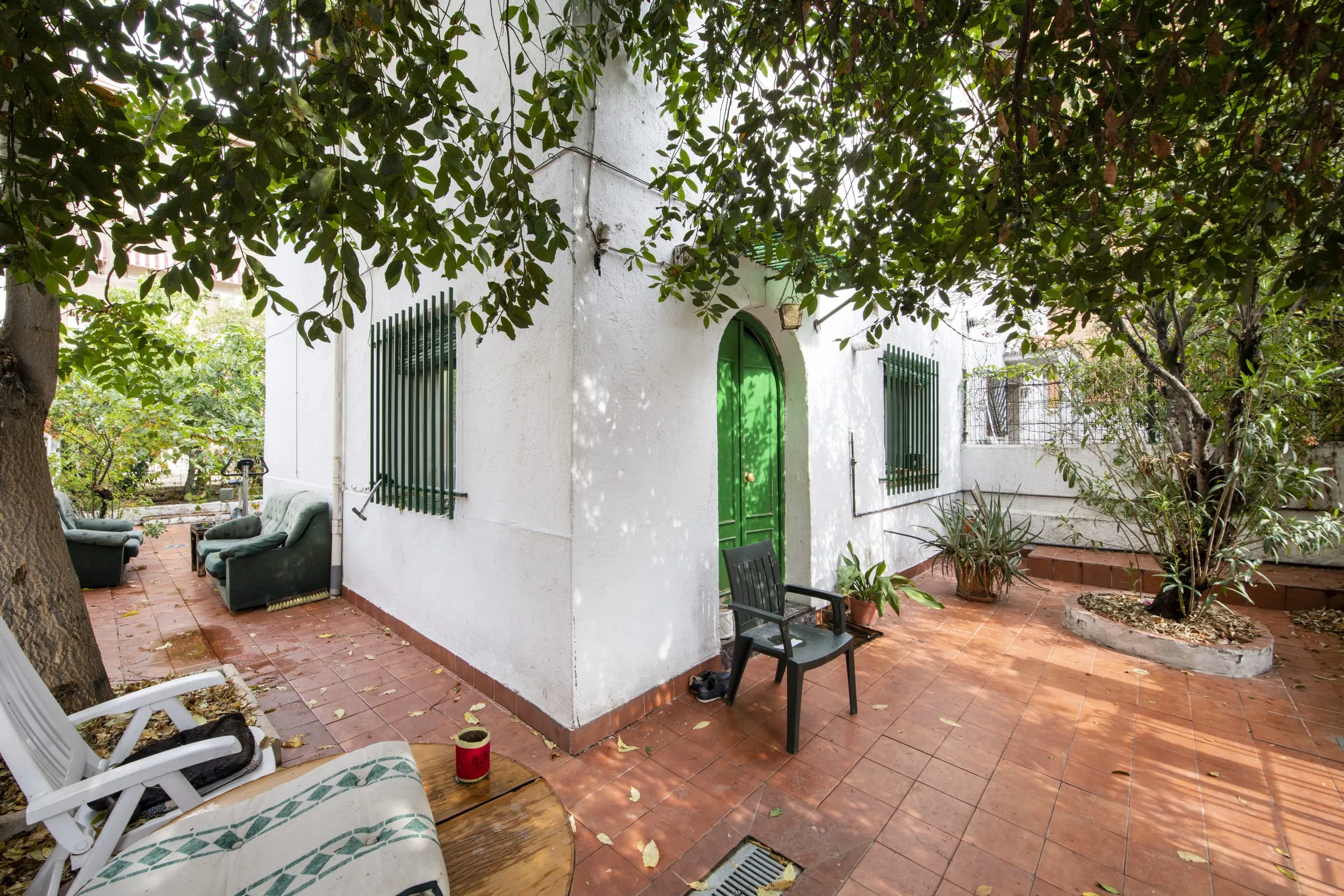 Terraza con suelo de barro junto a una casa de fachada blanca