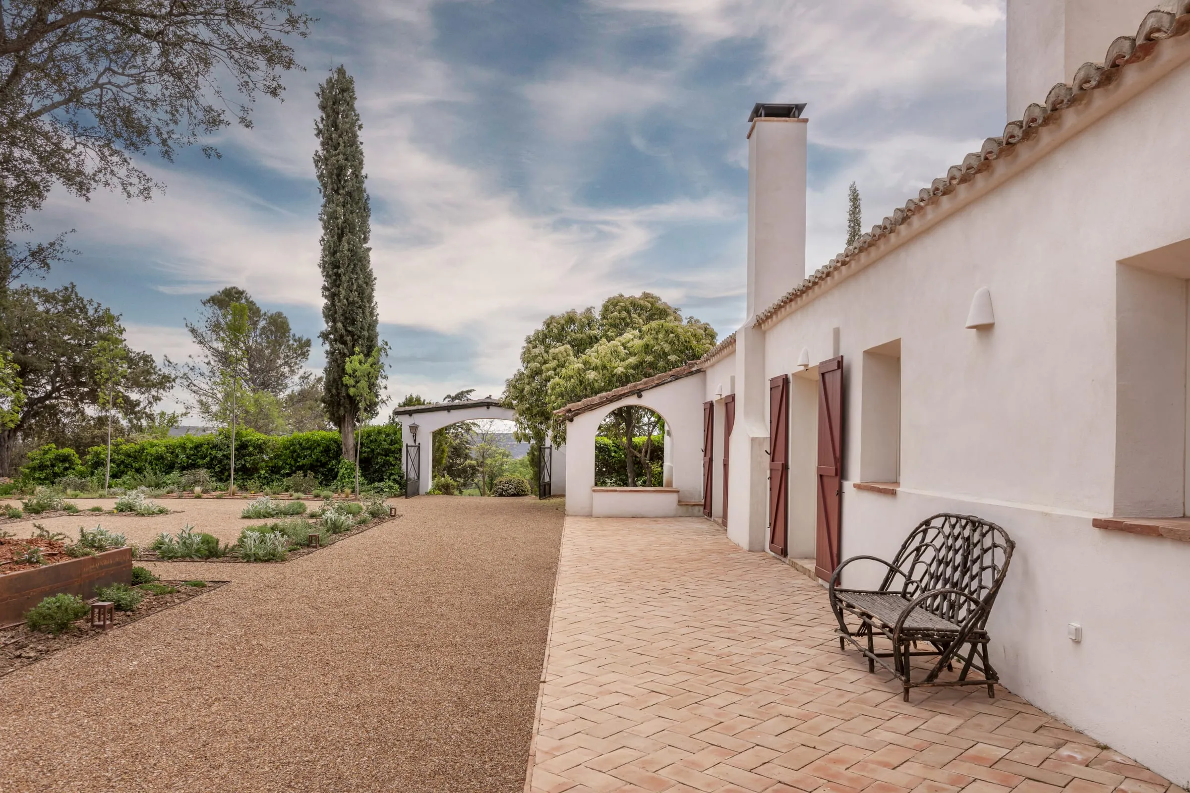 Casa de campo encalada con porche, suelo de barro y jardín