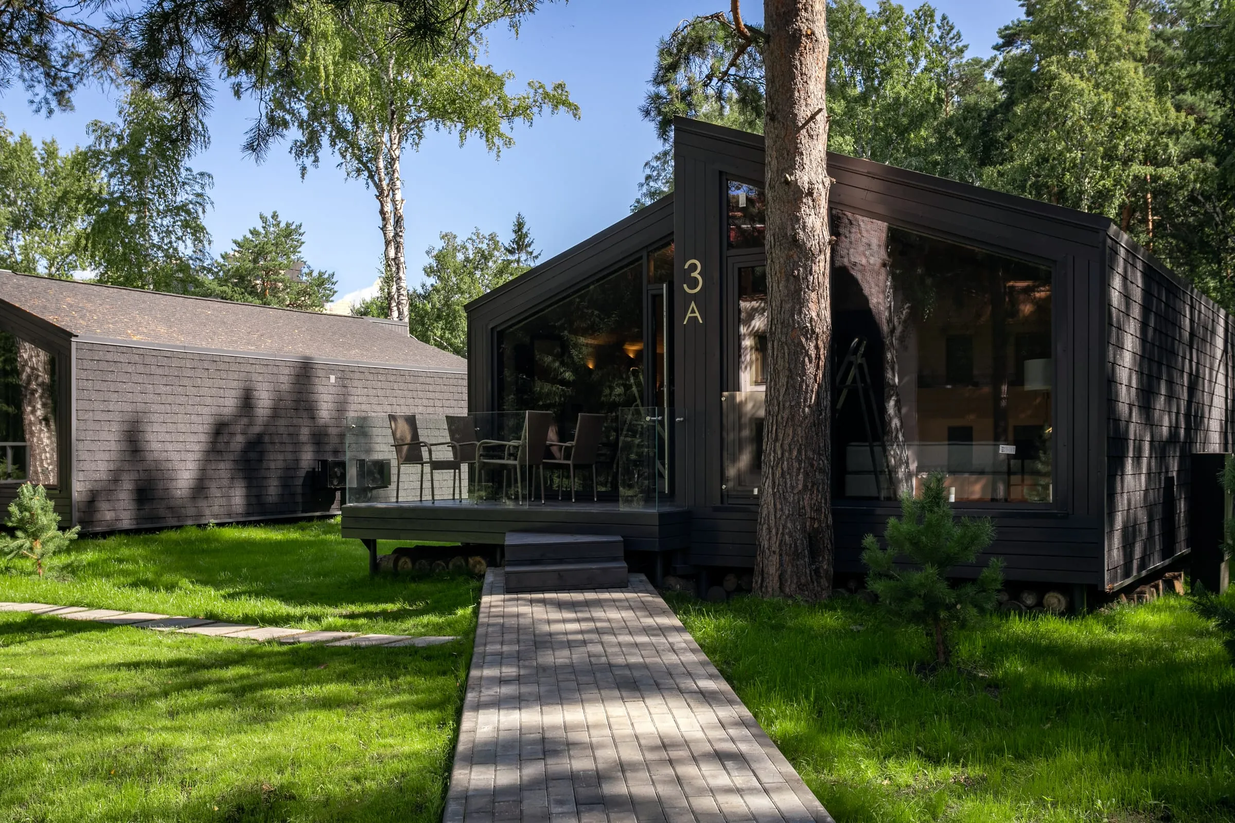 Casas de madera de fachada oscura y grandes ventanales entre árboles