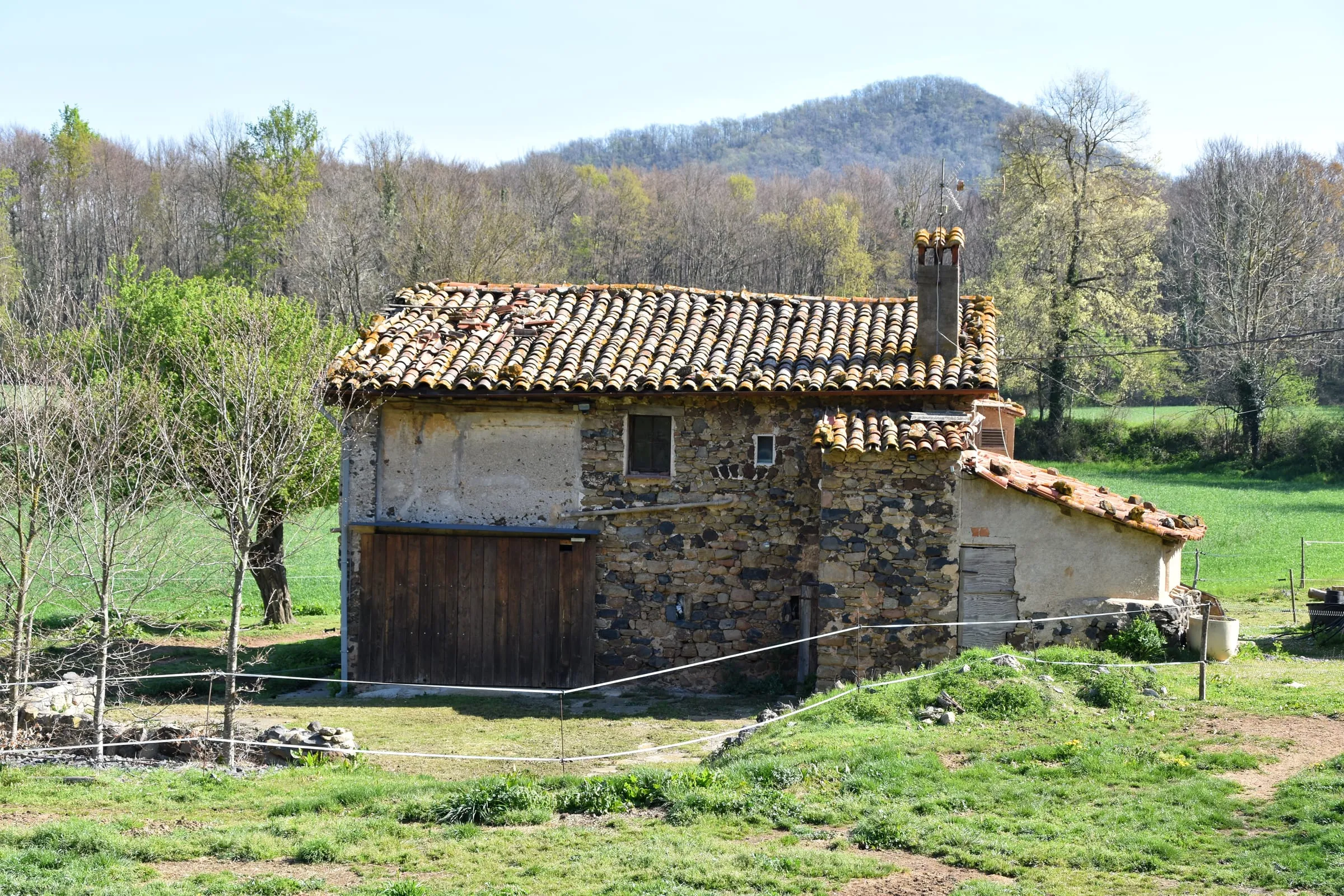 Casa de piedra con tejado de teja en el campo, con montes al fondo