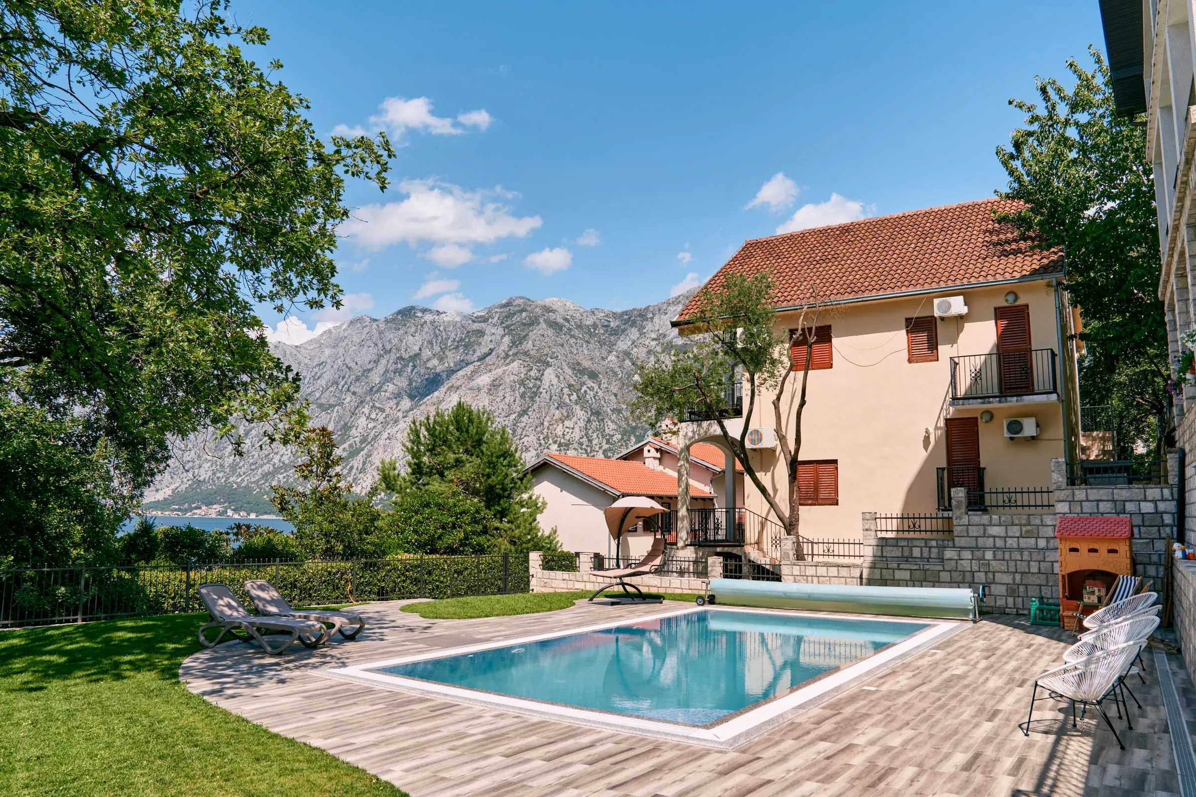Vivienda con piscina y jardín de césped con montañas al fondo