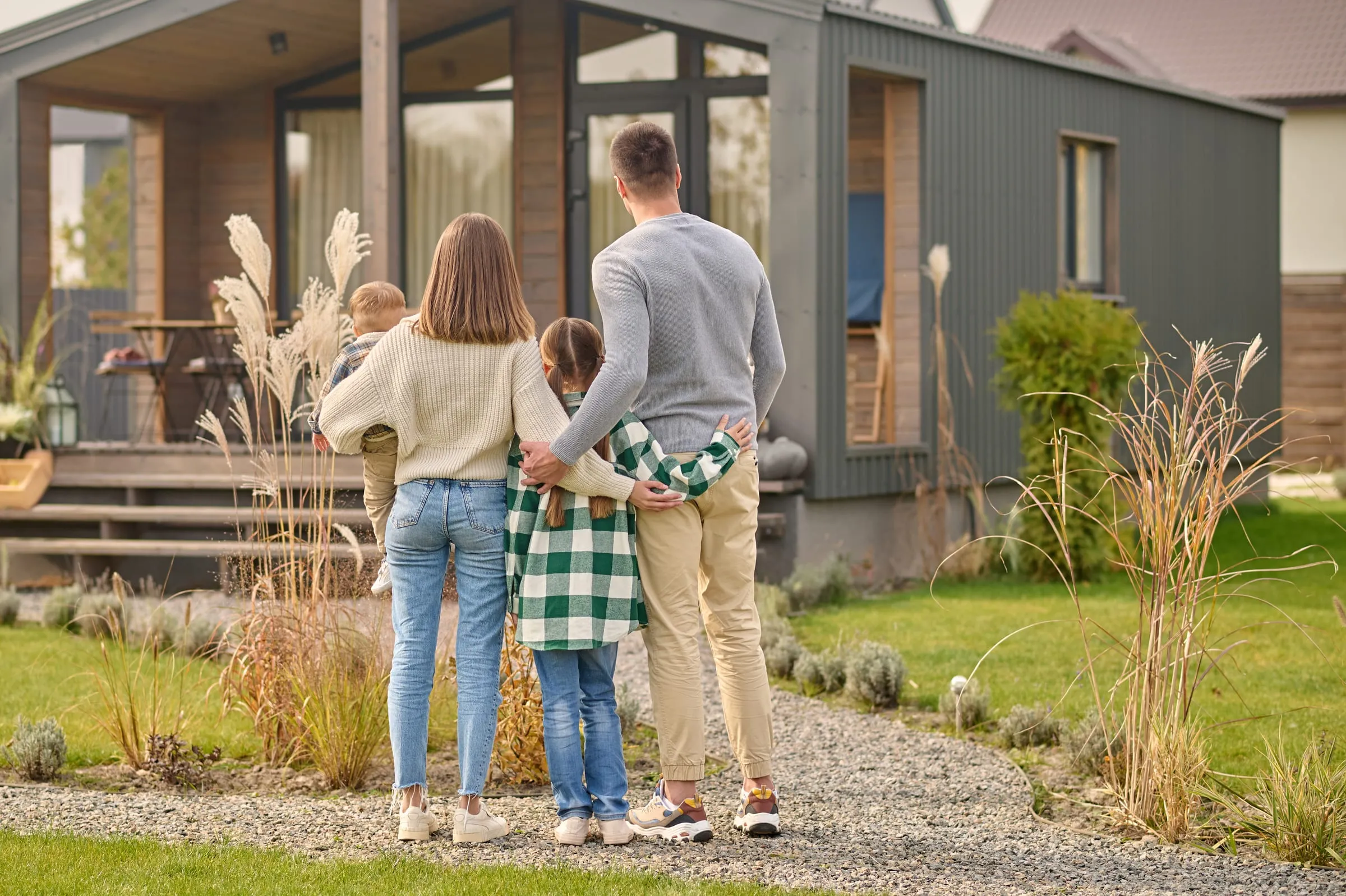 Familia abrazada mirando su casa nueva de una planta