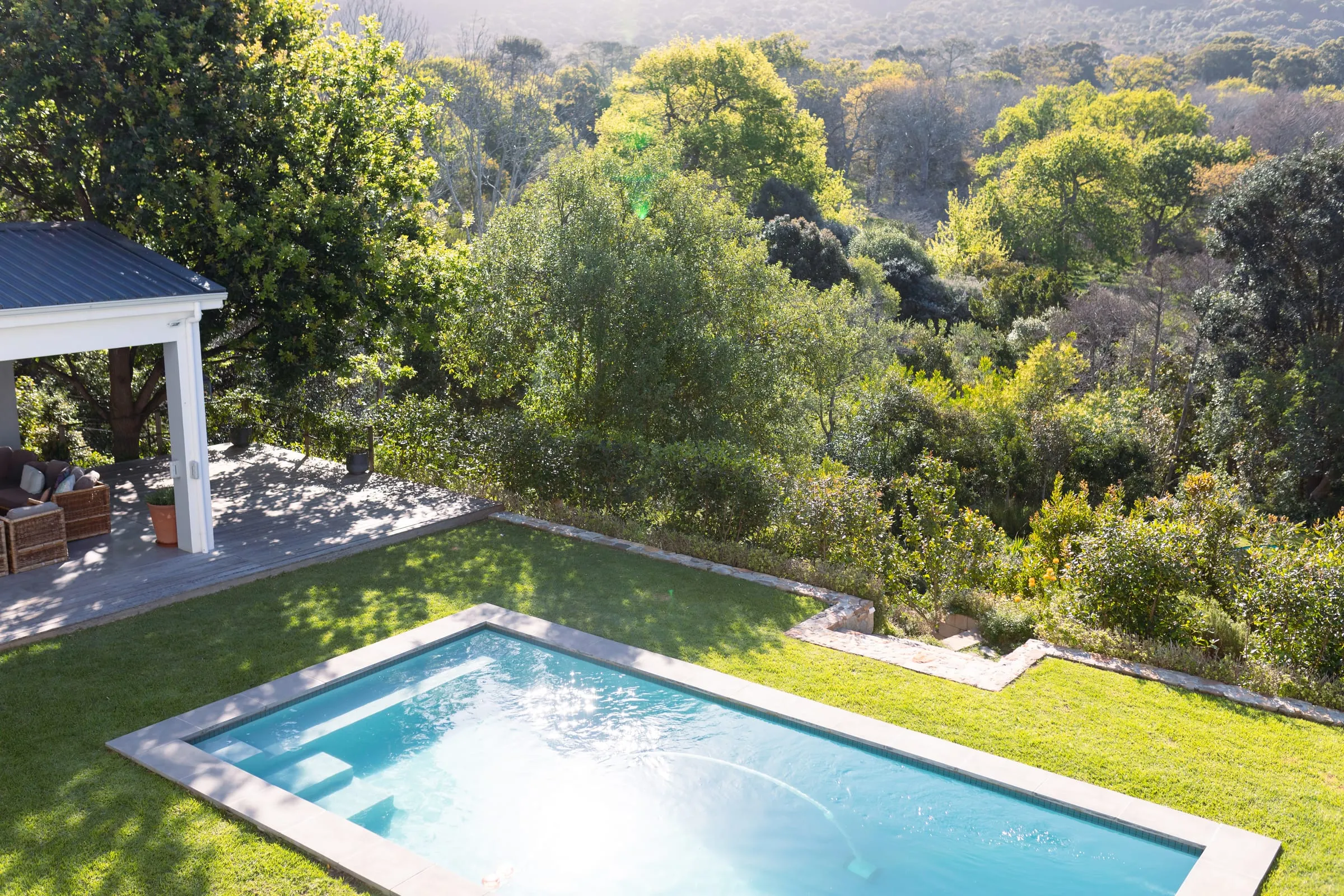 Jardín de césped con piscina junto a una vivienda